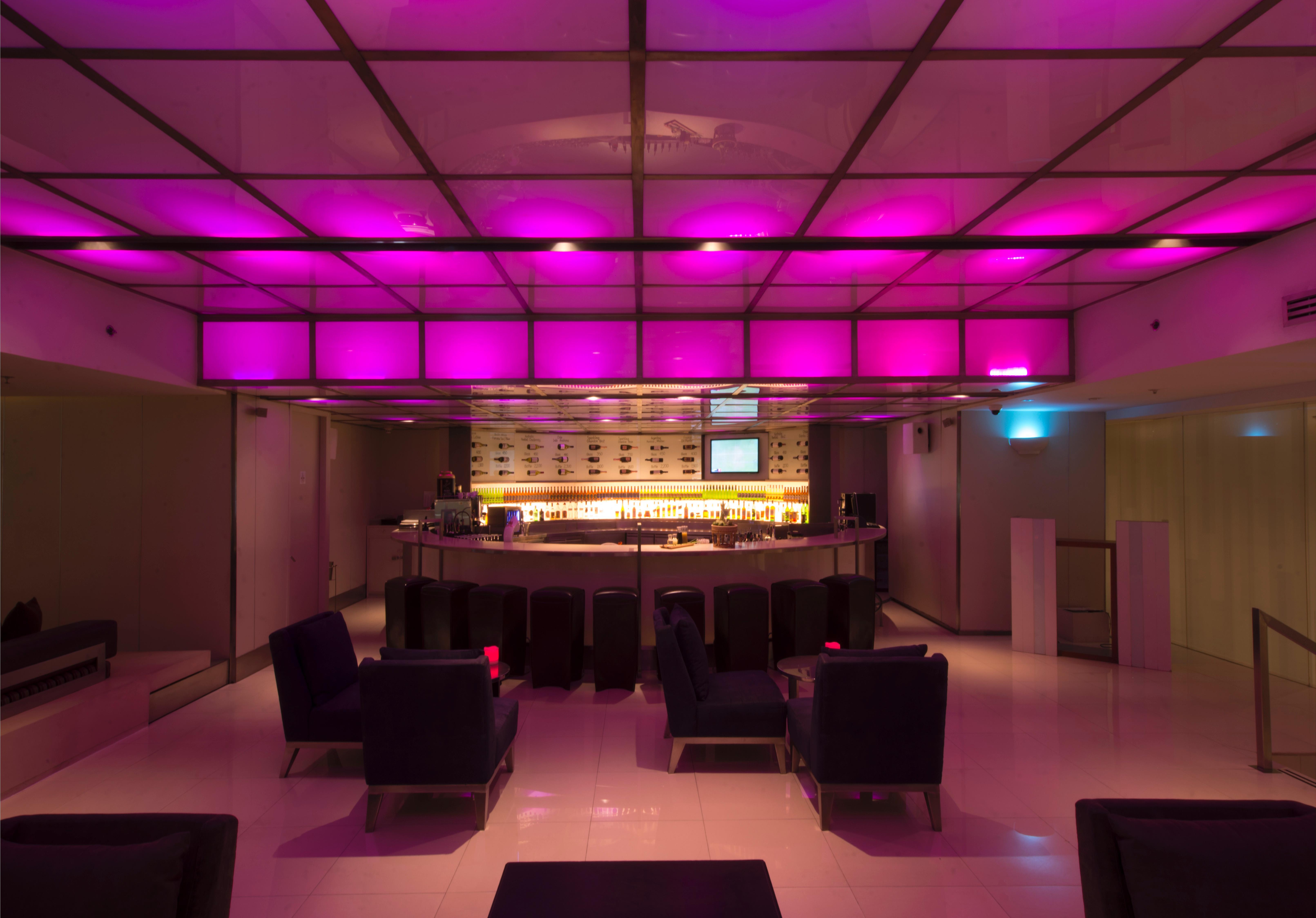 Pathumwan Princess Hotel - Sha Extra Plus Certified Bangkok Exterior foto The photo shows a modern bar interior with a sleek design. The lighting features a pink hue that illuminates the ceiling, creating a vibrant atmosphere. In the center, there is a rounded bar counter with a well-stocked shelf behind it. The seating ar