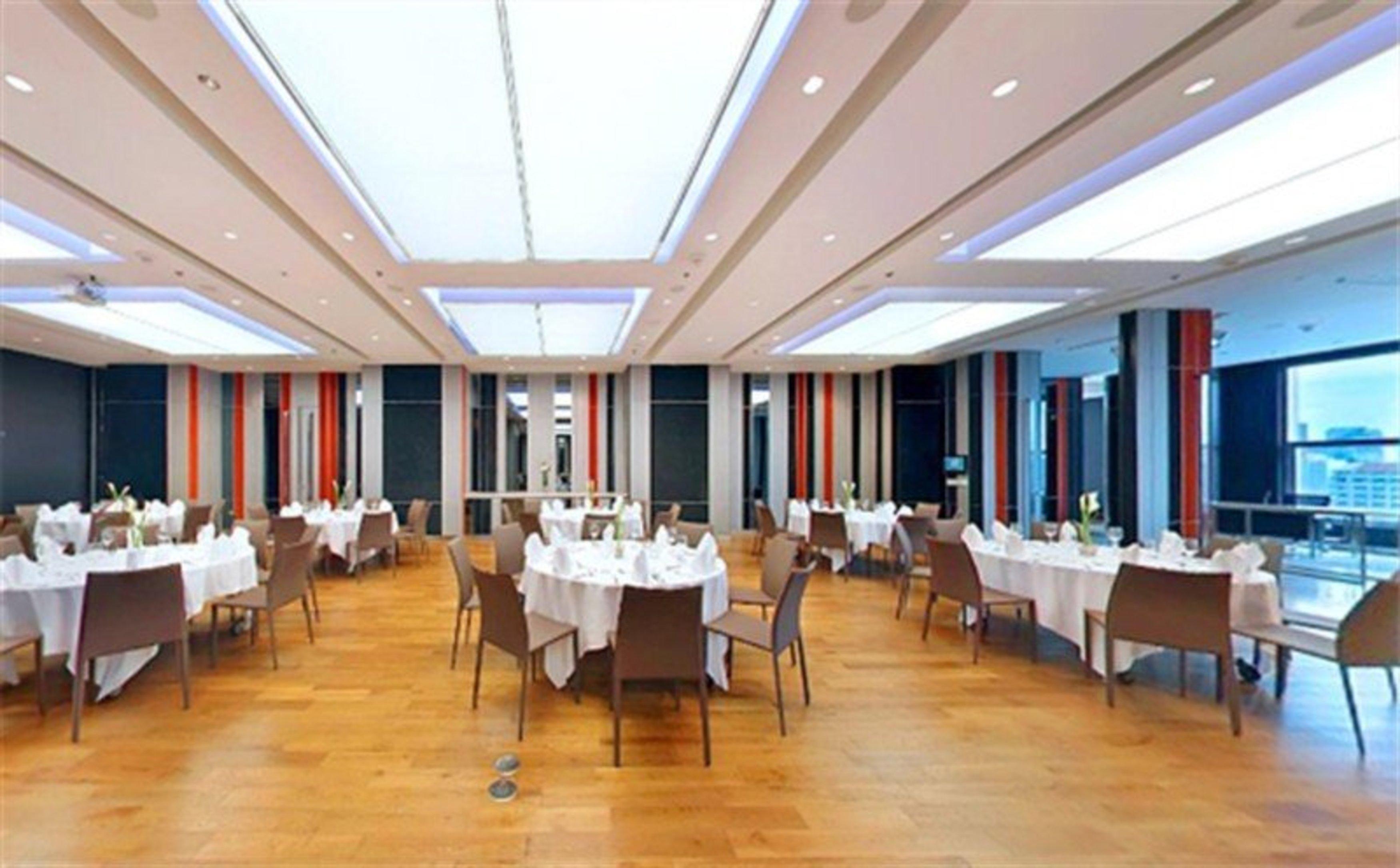 Pathumwan Princess Hotel - Sha Extra Plus Certified Bangkok Exterior foto The image shows a spacious restaurant or dining area. The floor is made of wooden planks, and the room features several tables, each covered with a white tablecloth and set for dining. The seating consists of modern chairs arranged around the tables.