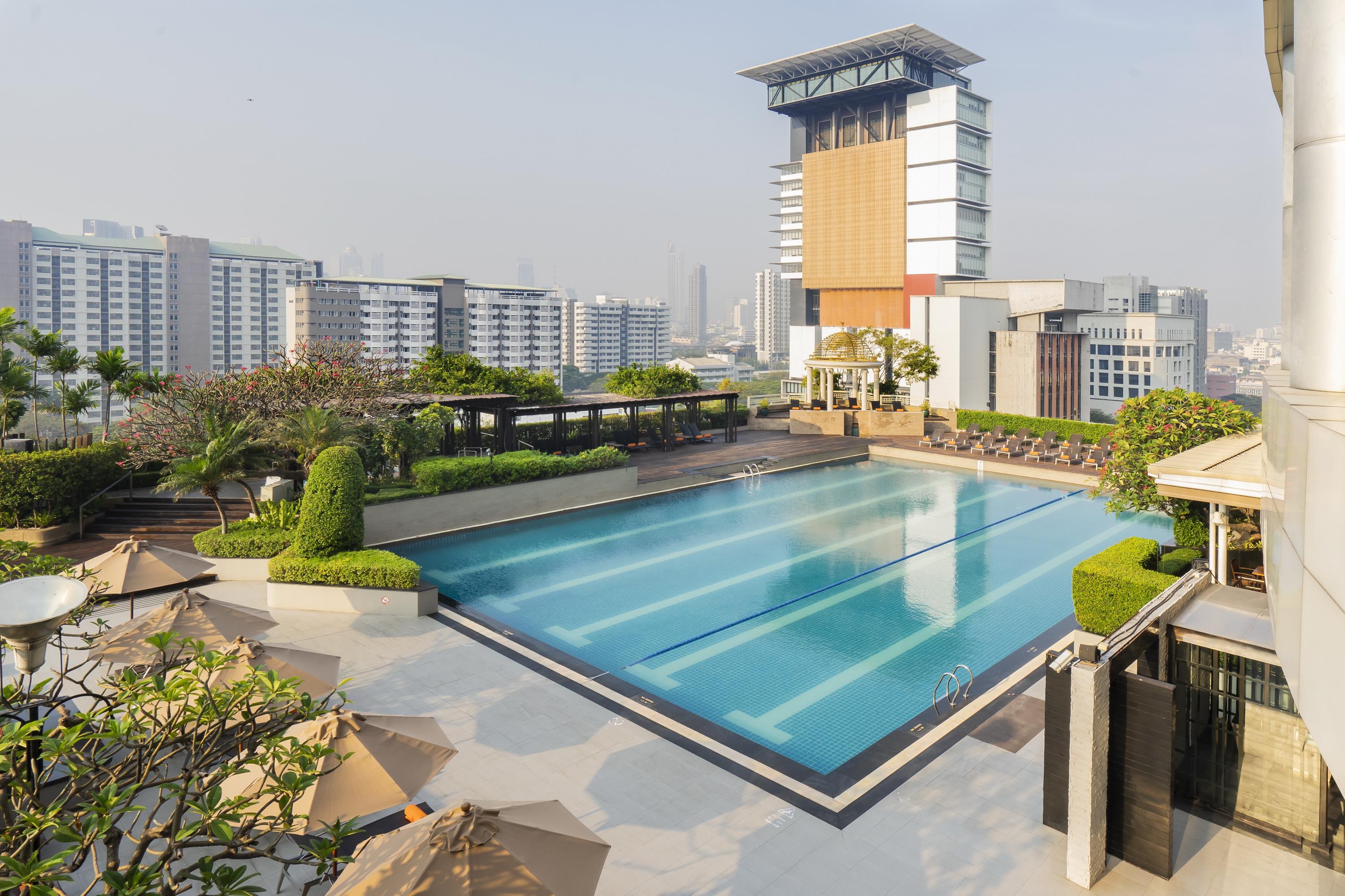 Pathumwan Princess Hotel - Sha Extra Plus Certified Bangkok Exterior foto The photo shows a modern swimming pool area situated on a rooftop or an elevated location. The pool is large and rectangular, with clear blue water and several swim lanes marked. Surrounding the pool are well-maintained green lawns and neatly trimmed