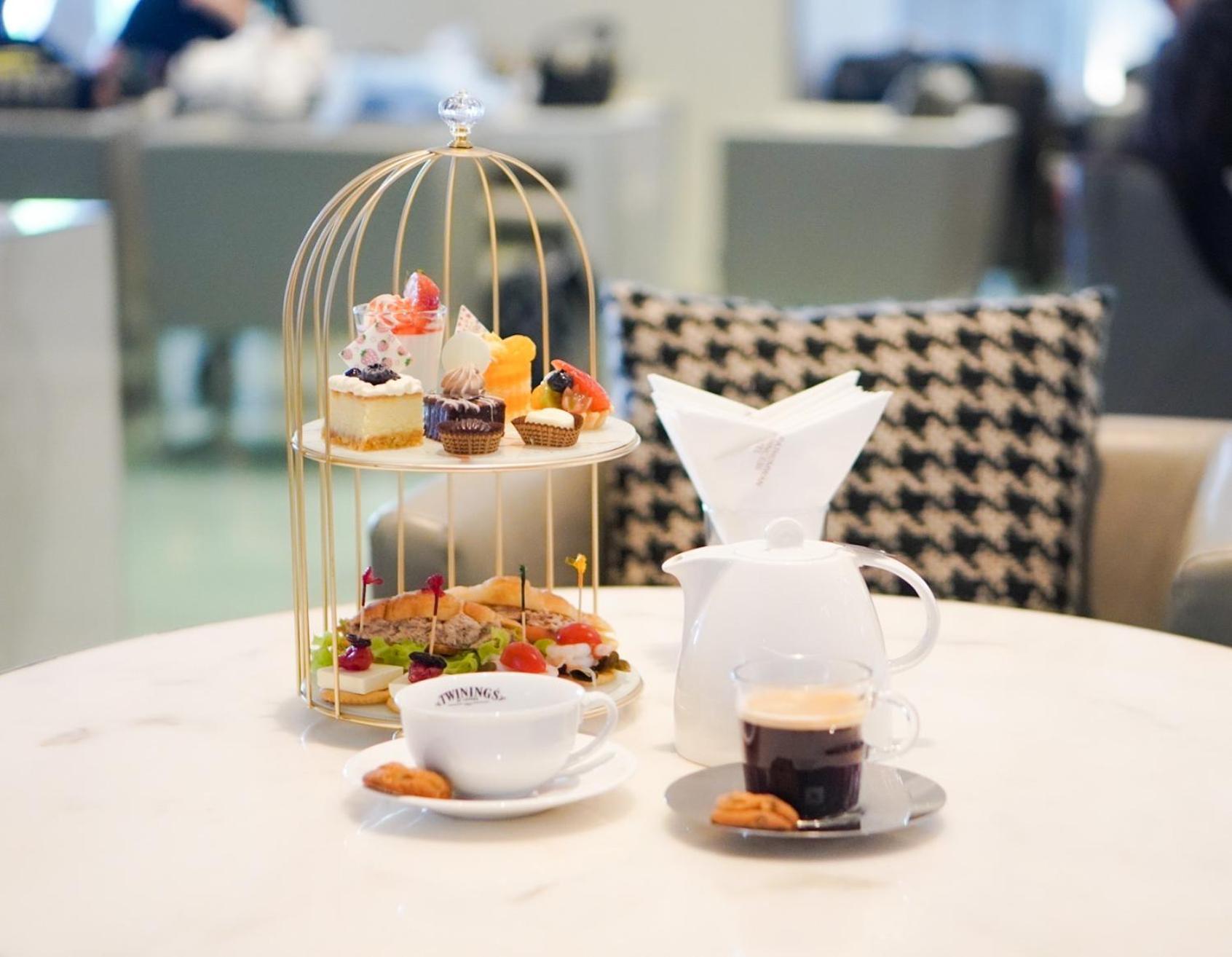 Pathumwan Princess Hotel - Sha Extra Plus Certified Bangkok Exterior foto The photo shows a beautifully arranged afternoon tea setting. At the center, there is a golden birdcage stand filled with an assortment of desserts, including pastries and small cakes, garnished with fruits. In front of the stand, there is a white te